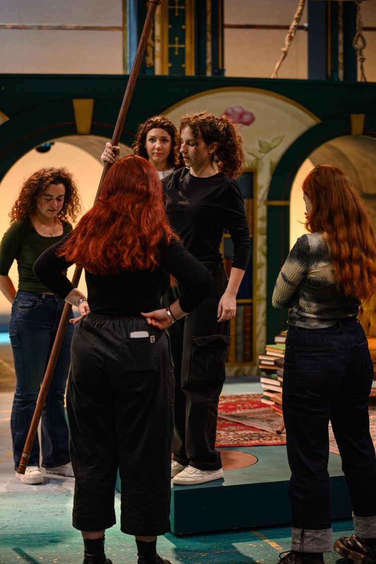 Group of Stage Management students on stage looking at the Assistant Stage Manager in the centre who is holding a long wooden pole